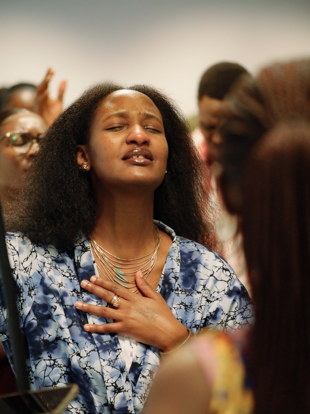 A woman worshiping with her hand on her heart